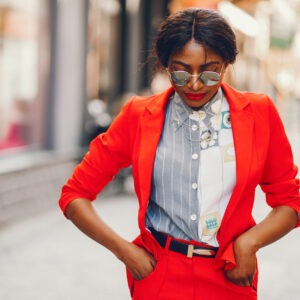 Elegant black woman standing in a summer city. Businesswoman in a red jacket